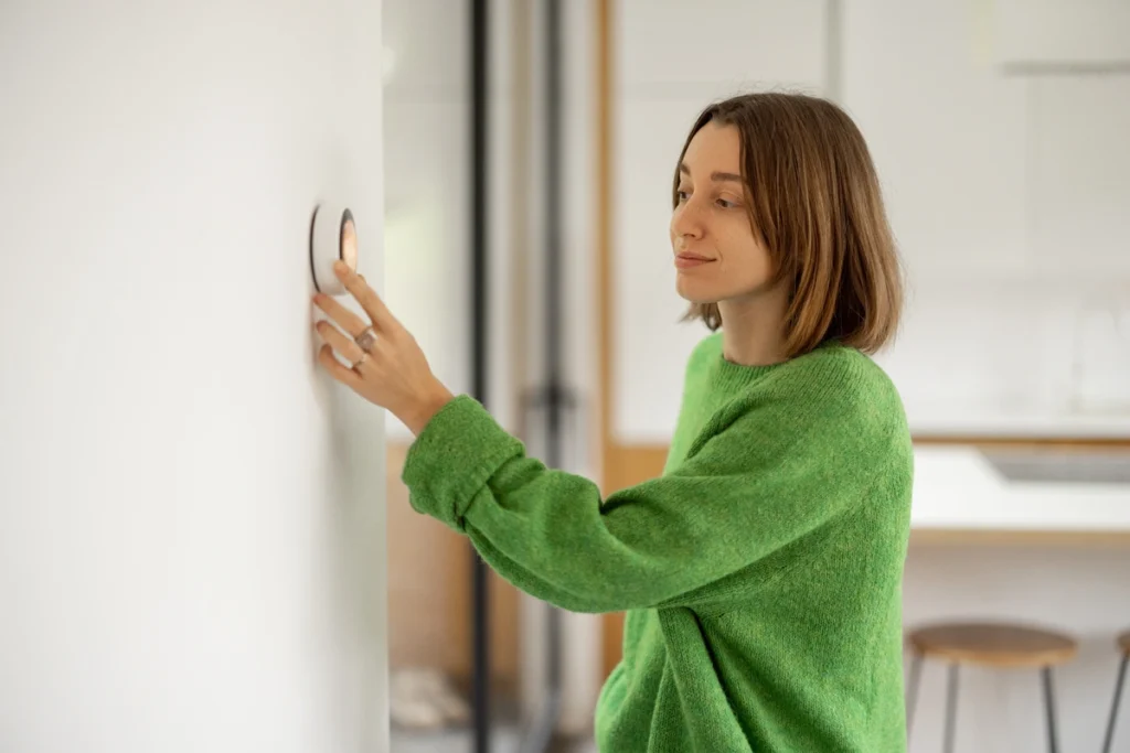 Woman checking her thermostat after cleaning AC unit