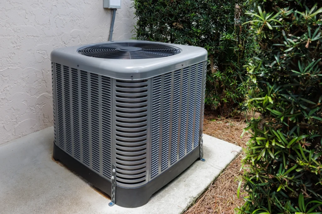 outdoor AC unit surrounded by greenery