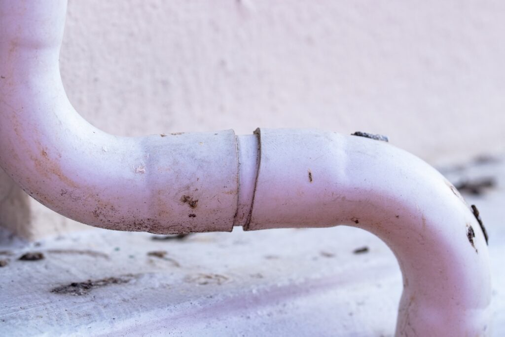 White plastic air conditioner drain pipe duct, wiring and plumbing in mall. Air conditioner pipe, wiring pipe, and plumbing pipe system. Air ducts and water pipes are installed on wall at outdoor.