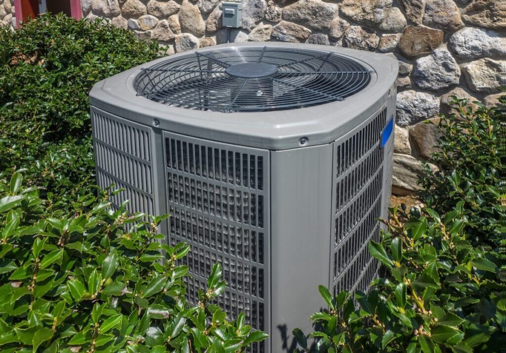 Air conditioning and heating unit for a residential house hidden by holly Air conditioning and heating unit for a residential house hidden by holly